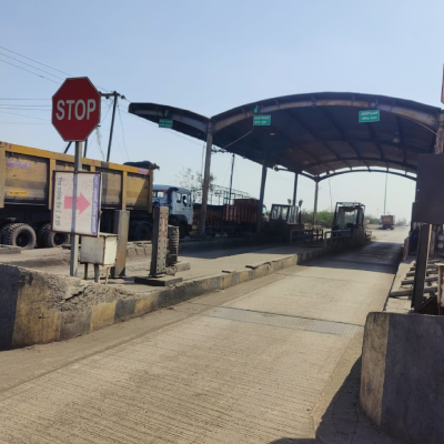 Toll plaza approach with STOP sign and waiting trucks at a Maharashtra FASTag site